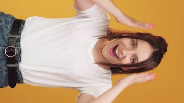 バーティカルビデオ ジェスチャー 成功する気分 パス試験 喜びの幸せな感情を表現する幸せな笑顔の若い女性 オレンジ色の背景に隔離された手のサイン — ストック動画