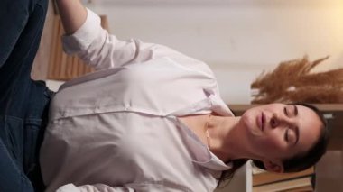 Dikey video. Evde yoga. Hafta sonu meditasyonu. Stres atmak. Rahat bir kadın Lotus pozisyonunda bağdaş kurup yerde nefes alma tekniği uyguluyor..