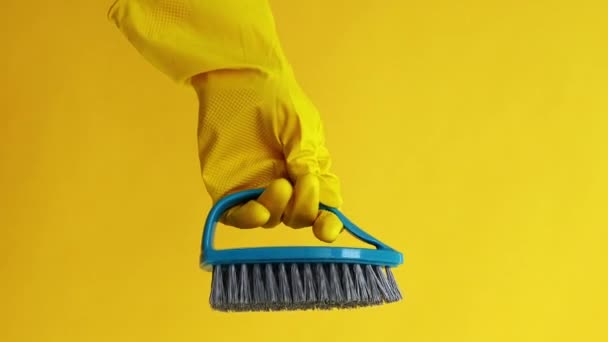バーティカルビデオ クリーニングツール 洗濯機について ホーム衛生について 黄色の背景に隔離されたブラシが付いている保護手袋の専門のジャンパー手 — ストック動画