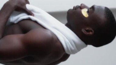 Dikey video. Yeni bir gün. İlham, tefekkür. Kendine güveni tam, altın gözlü, gömleksiz, bantlı beyaz banyo havlusu..