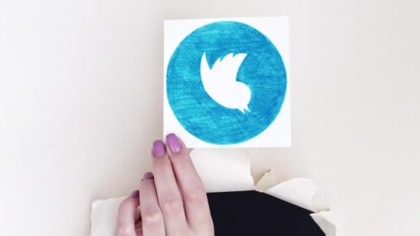 ハリコフ ウクライナ 2020年6月4日 垂直ビデオ ツイッターのサインだ ソーシャルネットワーク 女性インフルエンサー手で引き裂かれた画期的な壁紙穴保持アプリロゴ上のホワイトコピースペース — ストック動画