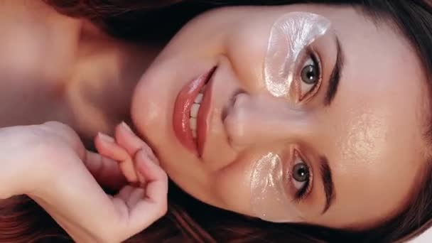 垂直录像 在眼皮底下化妆品补丁 减少皱纹 照料程序 护肤水凝胶胶原蛋白垫对恢复容貌满意的快乐女性 — 图库视频影像