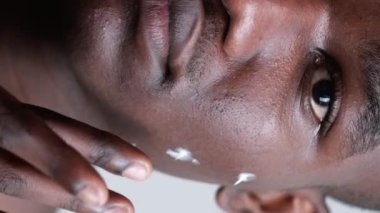 Dikey video. İnsan kozmetolojisi. Yüz bakımı. Erkek dermatolojisi. Kendine güveni tam yakışıklı adam temiz sağlıklı mükemmel cilde yüz kremi sürüyor..