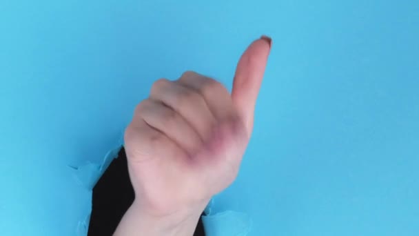 バーティカルビデオ ジェスチャーを支払う 急いで フリースペースループ付きブルーリッピング紙の壁の背景にあるブレークスルー穴の中の指のスナップでお金を要求する女性の手 — ストック動画