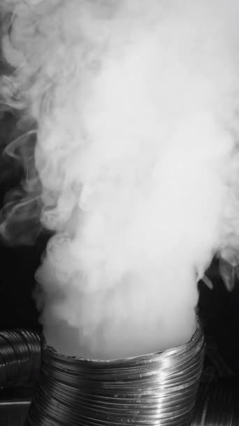 バーティカルビデオ 煙による汚染 化学フィルム スモッグエミッション ダークブラック抽象的な背景の柔軟な排気管からの白い産業ガスの流れの動き — ストック動画