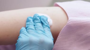 Dikey video. Aşı prosedürü. Virüs önleme. Sağlık hizmetleri. Tanımlanamayan doktor, hastanede iğne batırdıktan sonra kadın hastaya alçı yapıştırıyor..