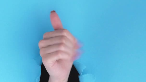 垂直录像 来做个手势给我蓝色撕破纸墙广告背景中空空隙的女性招手突破孔 — 图库视频影像