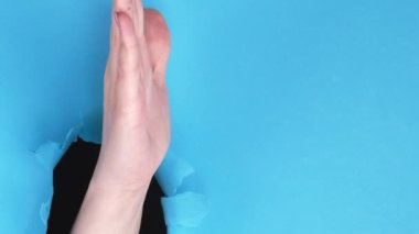 Dikey video. Reklamcı el. Sunum jesti. Kadın avucunun içi açık, delinme deliği mavi yırtık duvar zemininde, boş arkaplanı olan bir şey gösteriyor..