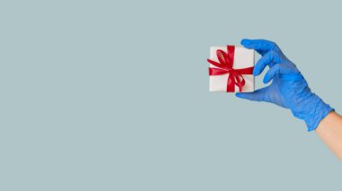 Pandemik doğum. Coronavirus Yeni Yılı. Mavi eldivenli kadın eldiveni mavi boş arkaplanda izole bir şekilde duruyor..