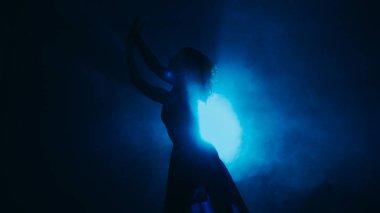Silüet performansı. Çağdaş dans. Şehvetli profesyonel koreograf kadın koyu mavi benekli arka plan fotokopi uzayında hareket ediyor.