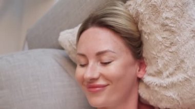 Dikey video. Gün rahatla. Dinlenmenin tadını çıkarıyorum. Tatmin olmuş bir bayan kanepede uzanıyor. Haftasonu uyanıyor. Haftasonu uyanıyor..