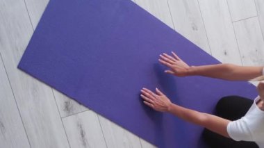 Dikey video. Kapalı alan sporu. Ev egzersizi. Atletik ince kadın spor yapıyor yoga minderinin üzerinde vücut esnetiyor ışık odası içinde sağlıklı bir yaşam tarzı..