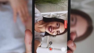 Dikey video. Kayıt blogu. Canlı yayın. Çevrimiçi iletişim. Neşeli kadın etkileyicisi içeriği filme alıyor. Vlog 'un ev içini çekiyor..