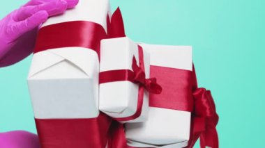 Dikey video. Salgın hastalık hediyesi. Virüs hazır. Koruyucu eldivenler içinde tanınmayan insan elleri, kapalı kutular tutarak mavi boş alan arkaplanını kutluyorlar.