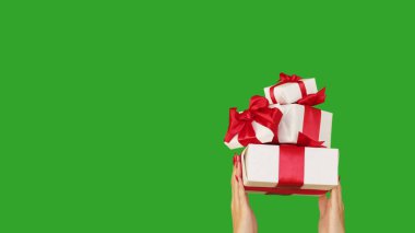 Hediye teslimatı. Tatil ikramiyesi. Yeşil fotokopi arkaplanından izole edilmiş kutuları tutan tanınmamış kadın elleri..