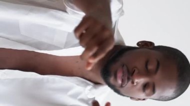 Dikey video. Eğlenceli bir yaşam tarzı. Yeni bir başlangıç. Pozitif tavır. Kendine güveni tam, tasasız, açık beyaz gömlekli bir adam. Aydınlık arka planda yeni günün tadını çıkarıyor..