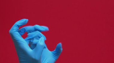 Dikey video. Noel hediyesi. Kutu şenliği. Koruyucu eldivenler giymiş iki el kırmızı arka planda izole edilmiş hediyeler veriyor..