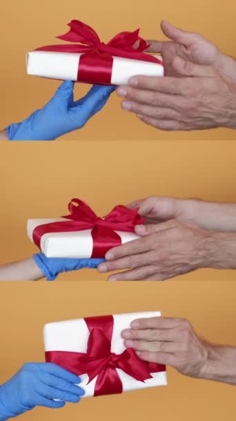 バーティカルビデオ クリスマスプレゼント ギフトサプライズ デリバリー衛生 黄色い背景ループで隔離された保護手袋で手で箱を交換する男のコラージュ — ストック動画