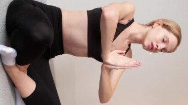 Dikey video. Yoga eğitimi. Stres atmak. Rahatlama tekniği. Nilüfer çiçeği pozunda bacak bacak üstüne atmış yorgun bir kadın yerde dinlenme egzersizi yapıyor..