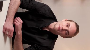 Dikey video. Başarılı insanlarız. Serbest çalışan bir girişimci. Modern ev işyerindeki laptopuyla güler yüzlü yakışıklı iş adamı..