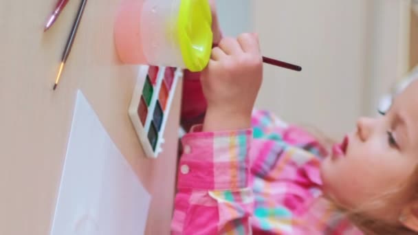 垂直录像 艺术幼儿园 儿童的创造力 专注的小女孩在孩子们的业余爱好空间 喜欢在纸上画水彩画 — 图库视频影像