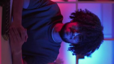 Dikey video. Reddeden adam. Meme ifadesi. Olumsuz cevap. Hippi adam, karanlık neon ışıklı odada çalışma masasının olmadığını söyleyerek başını sallıyor..