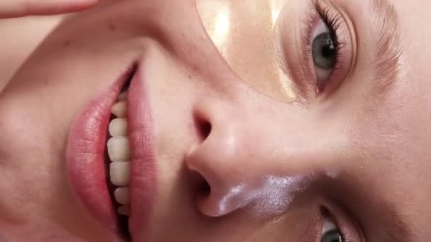 垂直ビデオ 眼帯だ 美容製品 皮膚治療だ 満足した笑顔の女性の閉鎖は 黄金のコラーゲンハイドロゲルマスクできれいな放射線顔に触れます — ストック動画