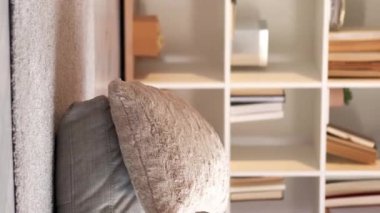 Dikey video. Evde rahatla. İçeride dinlenin. Tembel hafta sonu. Huzurlu, huzurlu, neşeli, genç bir kadın. Rahat oturma odasındaki rahat yastıklarda yatıyor..