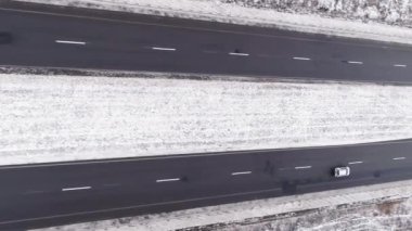 Dikey video. Hava kış pisti. Karlı yol. Beyaz donmuş orman bulutlu gün kırsal alanda yoldan geçen arabalarla asfalt kaldırımda..