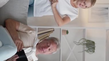 Dikey video. Aile masrafları. Ebeveynler destek oluyor. Bütçe harcamaları. Kibar baba tüm parayı mutlu kızına veriyor. Açık evdeki koltukta boş bir cüzdan olarak kalıyor..