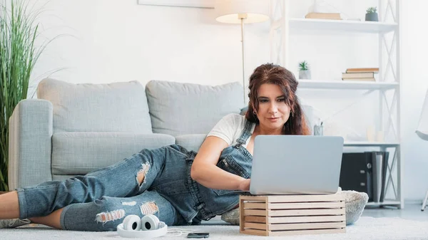 虚拟生活 快乐的女人计算机技术 中年妇女笑着把沙发放在灯室里翻动的笔记本电脑 — 图库照片