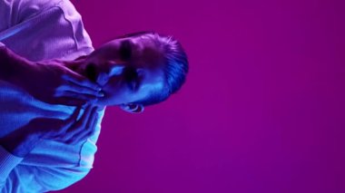 Dikey video. Diş ağrısı sorunu. Diş bakımı. Mavi renk neon ışığı ağrısından muzdarip hasta adamı rahatsız etti çene dokunuşu mor boşluk arkaplan.