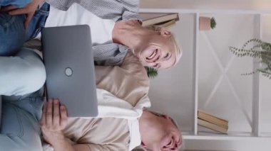 Dikey video. Çevrimiçi toplantı. Mutlu bir çift. Aile eğlencesi. Heyecanlı erkek ve kadın dizüstü bilgisayarda konferans veriyor..