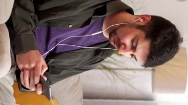 Dikey video. Telefon sorunu. Kötü internet. Mobil oyun. Evdeki kanepede bağlanma hatasından rahatsız olan, kulaklıklı sabırsız öfkeli adam atmaca oynuyor..