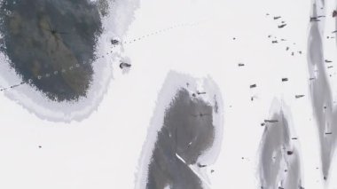 Dikey video. Hava karlı görünüyor. Kış Gölü. Donmuş beyaz su birikintileri bulutlu hava şartları sıkıcı sabah dronunda vahşi yaşam manzarası..