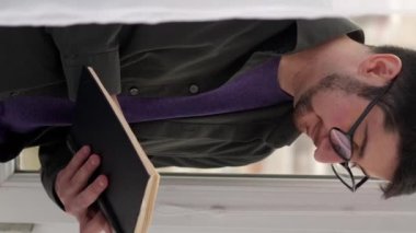 Dikey video. Boş vakitleri değerlendiriyorum. Edebiyat hobisi. Ev eğlencesi. Serene, gözlüklü hayalperest, hafta sonu vitrinde en çok satan kitap hikayesinin keyfini çıkarıyor..