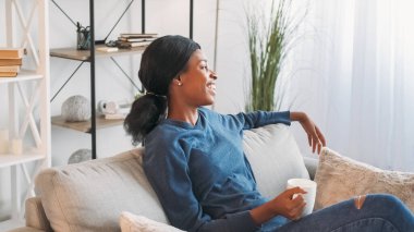 Kahve gevşedi. Hafta sonu istirahati. Ev atmosferi. Mutlu rüya gibi kadın çay içiyor. Oturma odasındaki rahat kanepede pazar keyfine bakıyor..