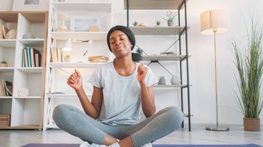 Egzersiz müziği. Sabah keyfi. Keyifli, rahat, genç bir kadın oturma odasında antrenmandan sonra fitness minderinde melodi eşliğinde dans ediyor..