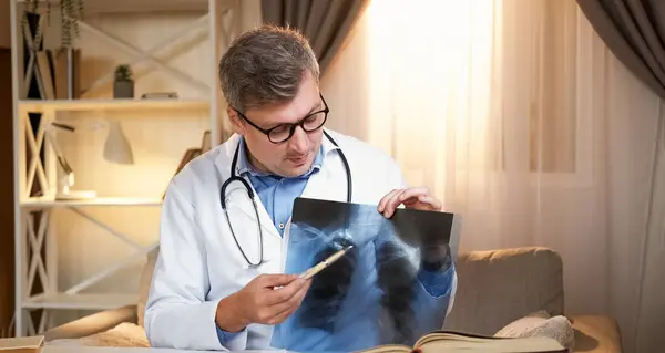 Radiography specialist. Diagnosis information. Smart medical doctor man explaining x ray film of pneumonia lungs sitting in modern office interior.