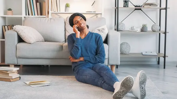 Mobile conversation. Home relax. Gadget lifestyle. Joyful carefree woman talking on phone enjoying cellular communication leisure indoors in living room.