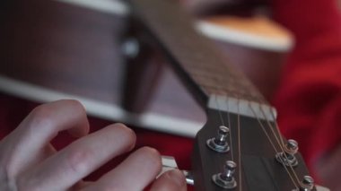 Dikey video. Alet ayarlama. Profesyonel gitarist. Yaratıcı sanatçı parmaklarını kulaklık müzik ekipmanlarının vidalarını ve dişlilerini düzelterek uzattı.
