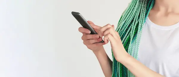 Creative hairstyle. Mobile chat. Unrecognizable woman with mint blue hair braids using smartphone browsing internet isolated on white copy space background.