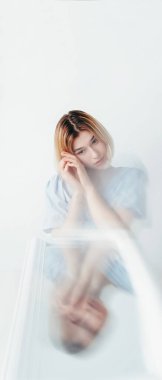 Duygusal bozukluk. Psikoloji problemi. Ayna yansımasındaki düşünceli genç kadın beyaz arka plandaki boşlukta iç çatışma hissediyor.