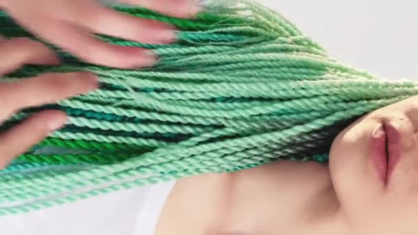 バーティカルビデオ 民族的な夢 明るいヘアスタイル 白い背景に隔離された青い緑色の色の毛のねじれの編組が付いている認識できない女性 — ストック動画