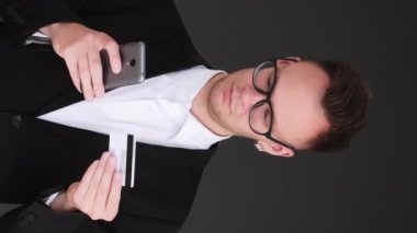 Dikey video. Mobil bankacılık. Çevrimiçi işlem. Elektronik ödeme için telefon uygulaması kredi kartı CVV kodu kullanan bir işadamı..