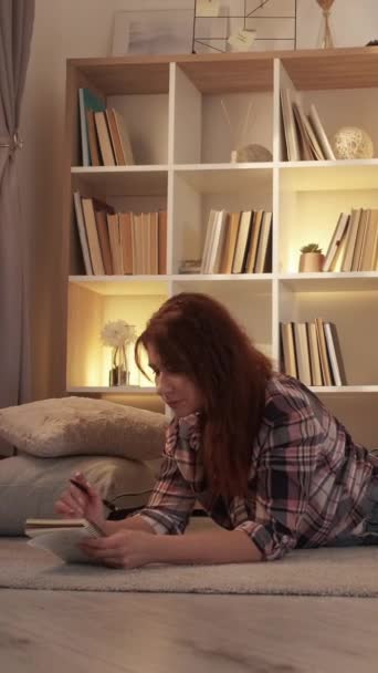 バーティカルビデオ 女性日記 ロマンチックな気分 ホームレジャー ライトルーム内で居心地の良い雰囲気の中で床を敷く中年女性 — ストック動画