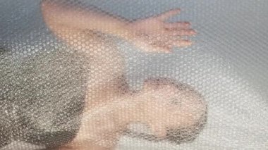 Dikey video. Plastik yeniden kullanım. Ekoloji problemi. Çevresel atık azaltma sanatı. Yumuşak kadın silueti baloncuk ambalajlı duvara dokunuyor..