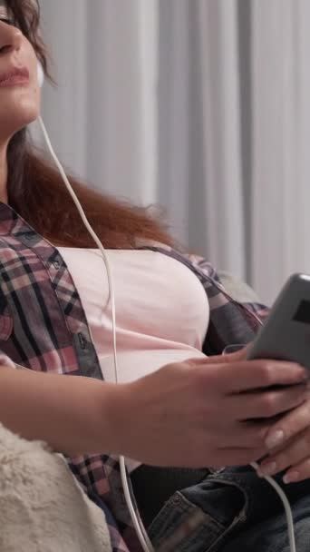 비디오 애호가 평온한 모바일 헤드폰에 숙녀는 가벼운 인테리어에 스마트 소파에 — 비디오