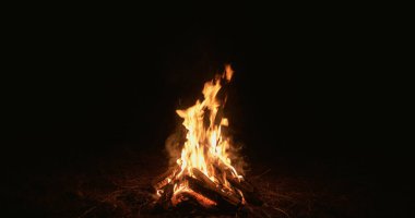 Gece ateşi. Siyaha ateş. Odaklanamayan sarı renk yanan odun, yanan odun, karanlık boşluk arka planında sıcak ateş dumanı..