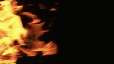 Dikey video. Yanan ateş. Alev dokusu. Sarı turuncu renkte, parlayan kamp ateşi siyah karanlık gece fotokopi arka planında hareket kıvılcımları oluşturur..